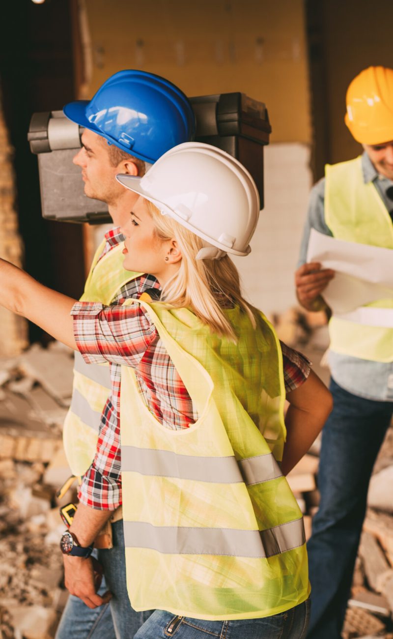 Four construction architects review plans of building damaged in the disaster. Pointing at damages. Selective focus.