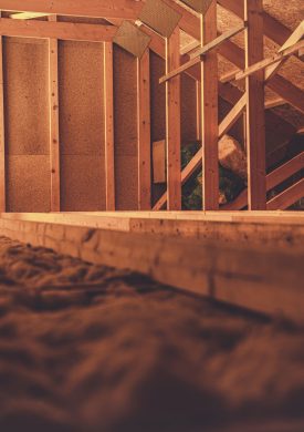 Caucasian Construction Worker in His 40s in the Newly Built Wooden House Attic. Wood Building Theme.